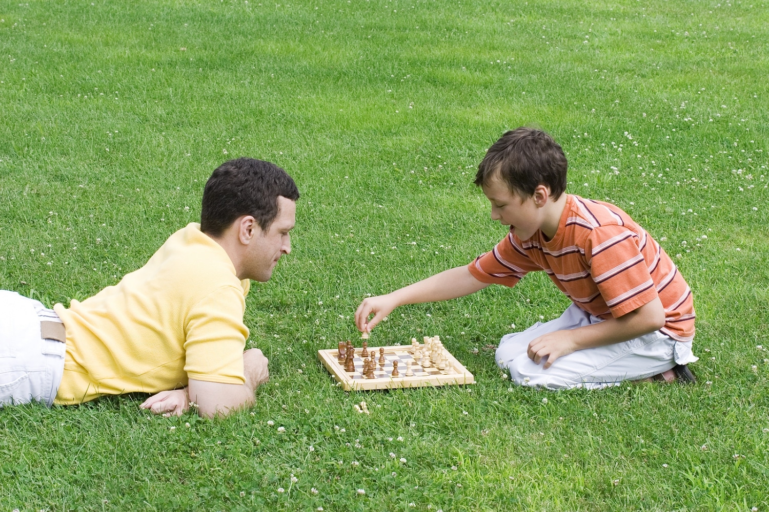 man and boy playing chess on grass
