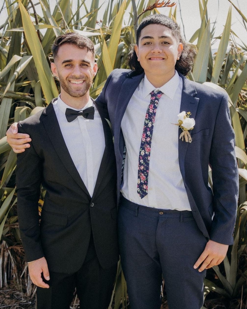 A man and a boy in formal suits hugging and smiling happily