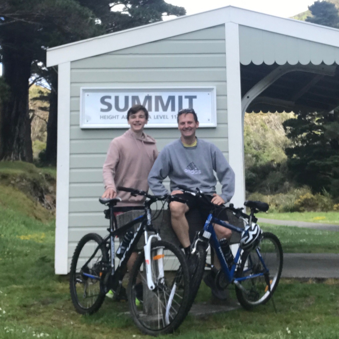Young man and man standing with bikes in front of an old building