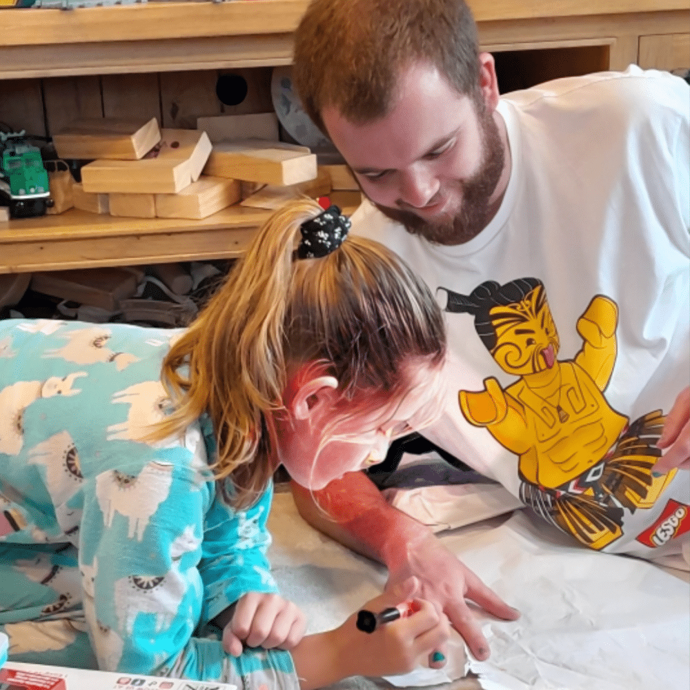 Man and young girl colouring together happily