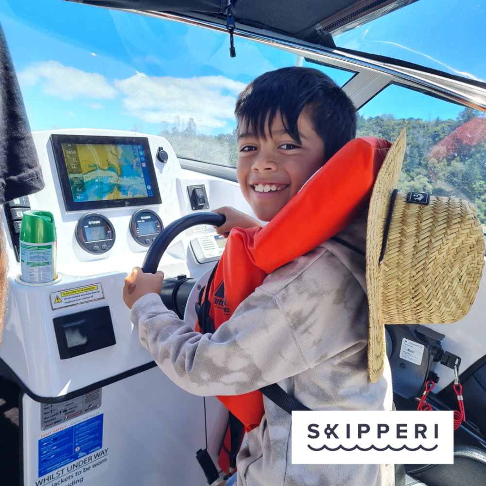 Young boy with life jacked at the steering wheel of a bot on a sunny day