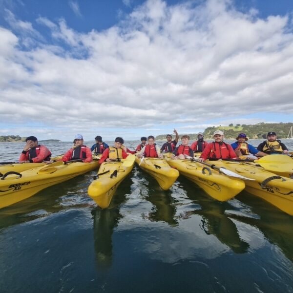 Boys sitting in yellow kayaks looking at the camera