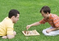 man and boy playing chess on grass