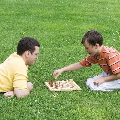 man and boy playing chess on grass