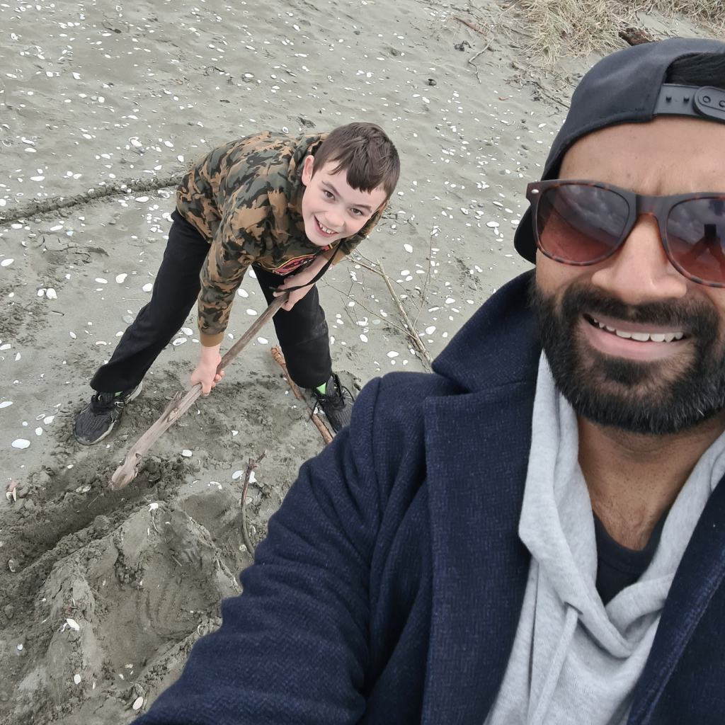 Ruvin and Caleb are at the beach and smiling up at the camera